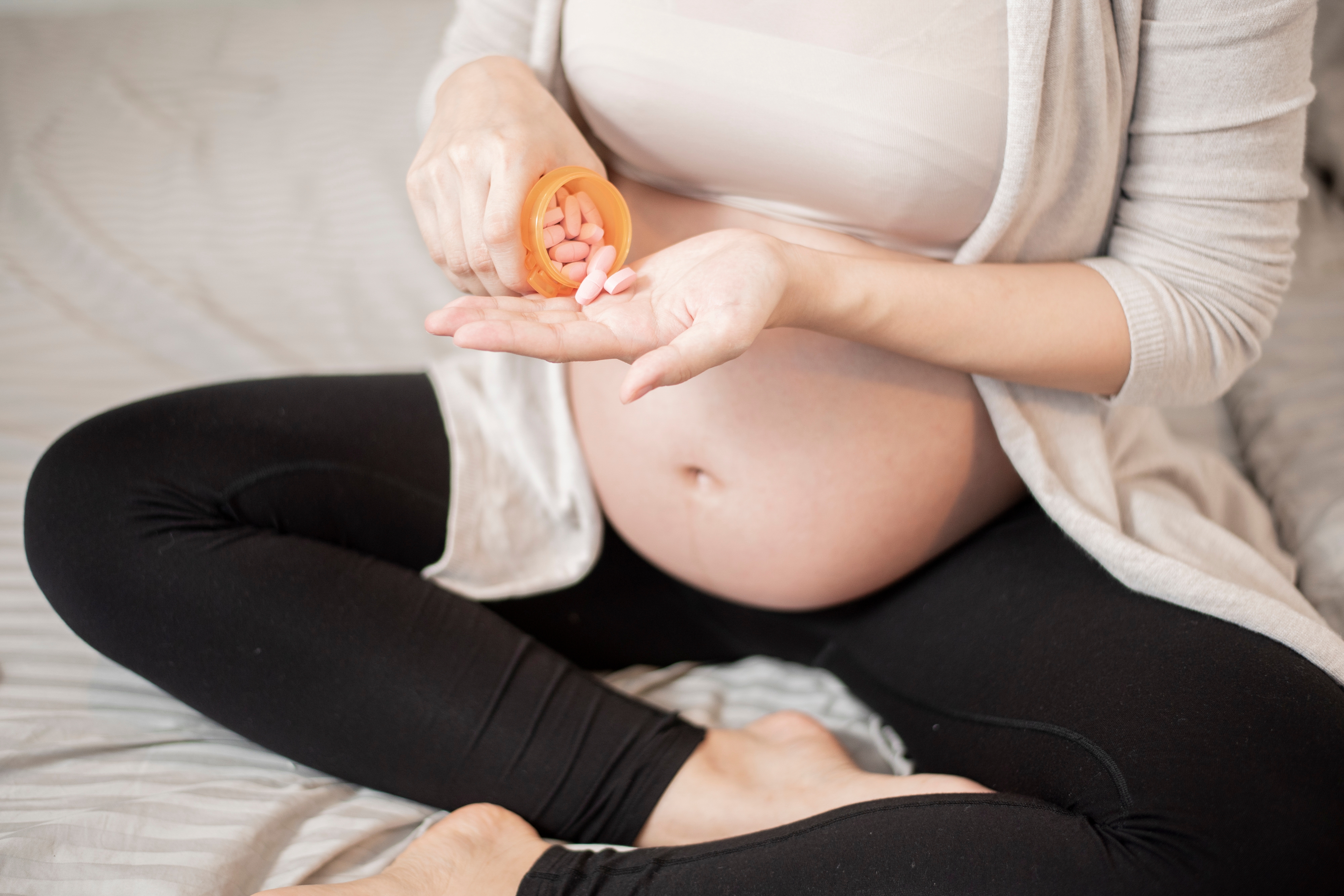 Close up pregnant woman taking pills