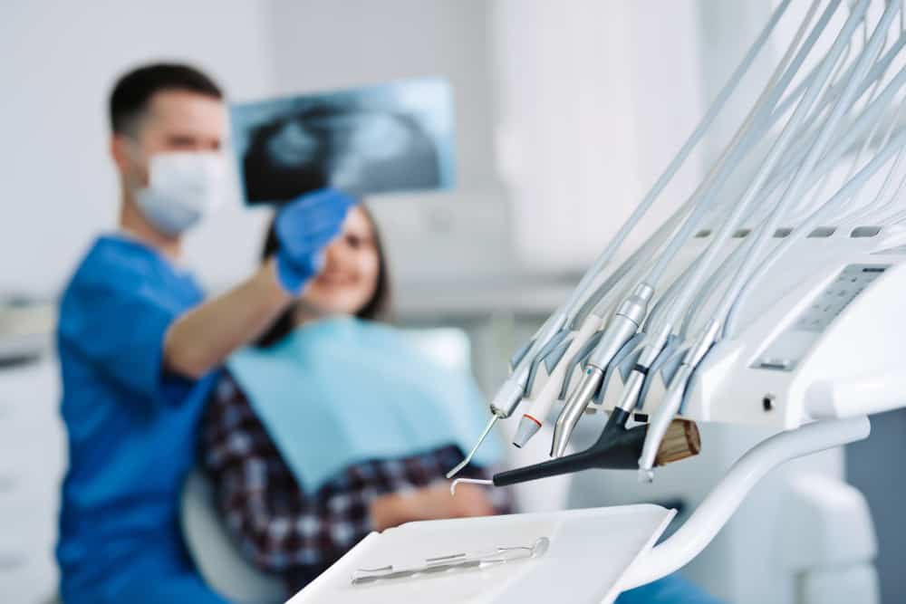 Dental,Instruments,With,Dentist,And,Patient,Looking,At,X-ray,On